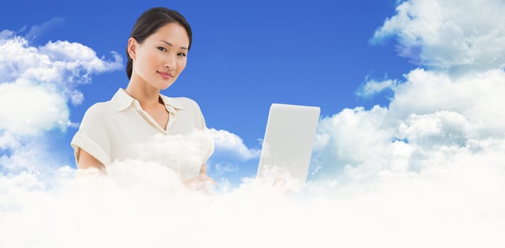Asian businesswoman using laptop against scenic view of blue sky