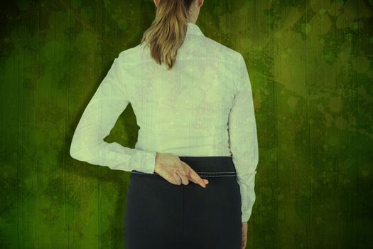 Rear view of businesswoman with fingers crossed over white background against green paint splashed surface