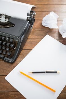 Picture of a type writer with paper and pen