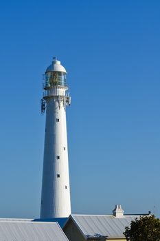 The slangkop lighthouse tower towering over rooftops with clear blue sky, Cape Town, South Africa