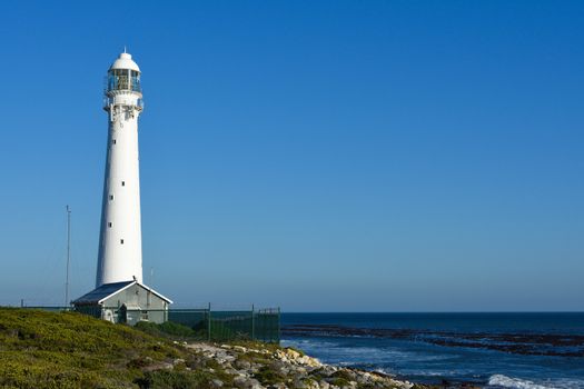 The tall white lighthouse at slangkop overlooking the Atlantic ocean, Cape Town, South Africa