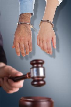 Closeup of handcuffed business people against digital image of gray wall