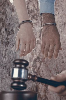 Closeup of handcuffed business people against dirty old wall background