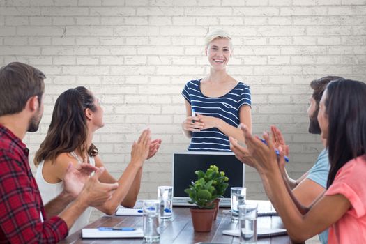 Colleagues clapping hands in a meeting against white wall