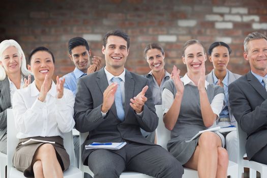 Business people applauding during meeting  against brick wall