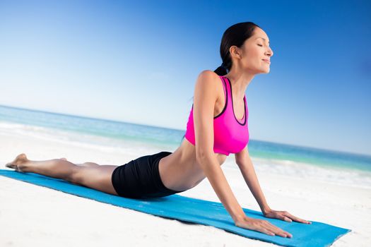  Fit woman doing yoga on the beach