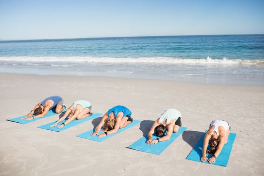 People doing yoga on the beach on a sunny day