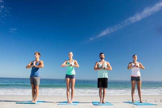 People doing yoga on the beach on a sunny day