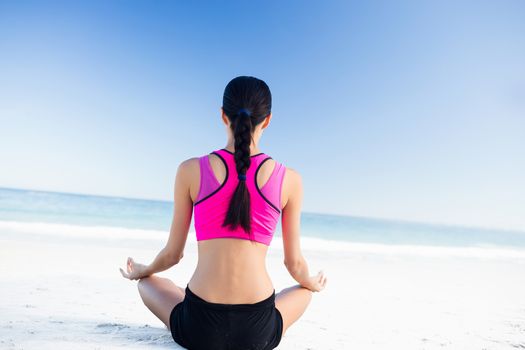 Woman doing yoga on the beach on a sunny day