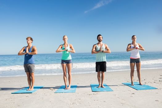 People doing yoga on the beach on a sunny day