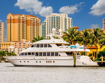 A large white yacht on a canal in front of a condominium