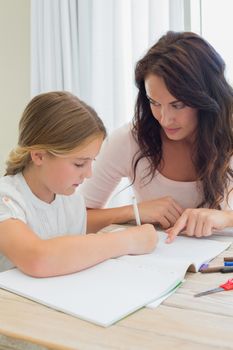 Mother assisting daughter in homework at table in house