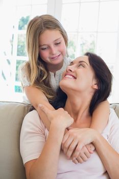 Smiling mother looking at loving daughter in house