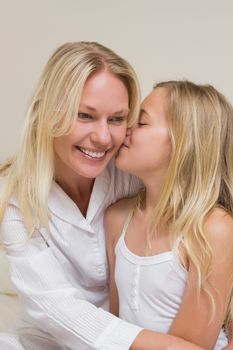 Cute girl kissing mother on cheek at home