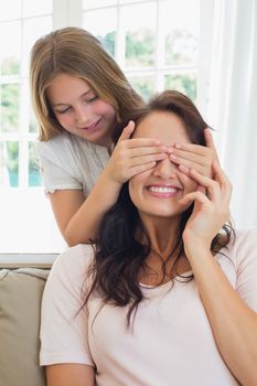 Cute girl covering eyes of mother in house
