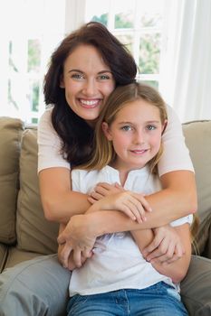 Portrait of loving mother and daughter on sofa at home