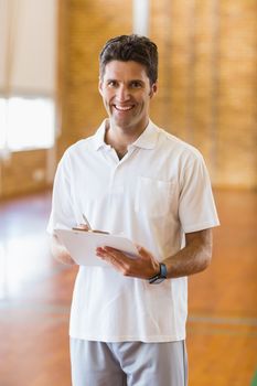Portrait of smiling sports teacher holding clipboard in school gym