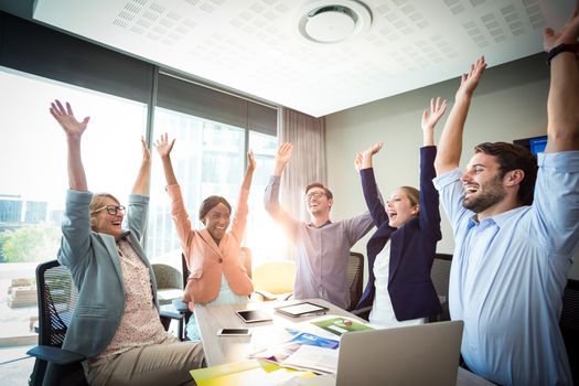 Business people raising their arms during meeting in the office