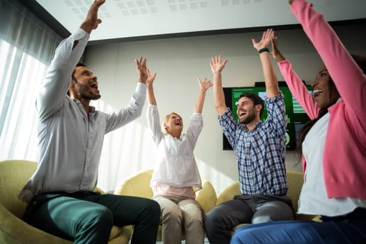 Business people raising their arms during meeting in the office