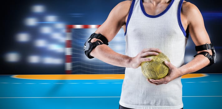 Mid section of athlete man holding ball  against handball field indoor 