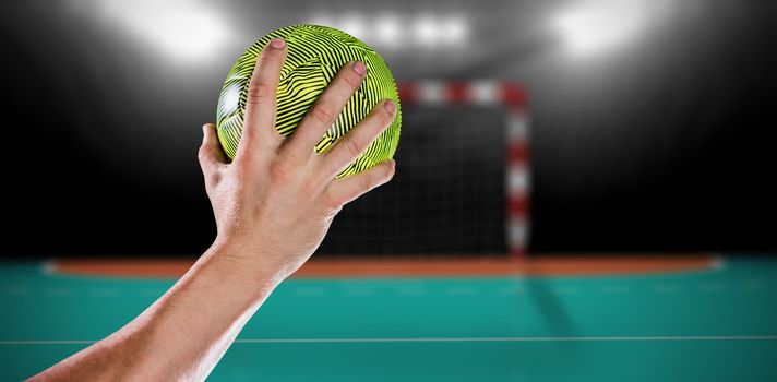 Sportsman holding a ball against handball field indoor 