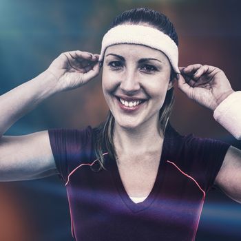Female athlete wearing headband and wristband against colored background