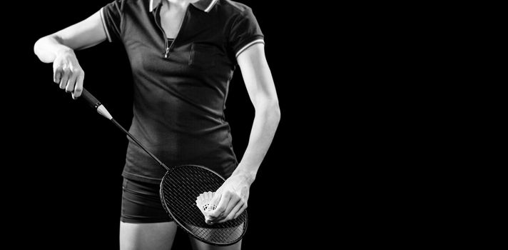 Badminton player holding a racquet ready to serve on black background