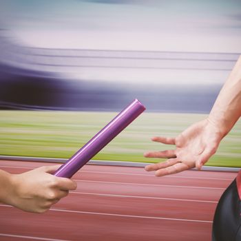 Athlete passing a baton to the partner in the stadium