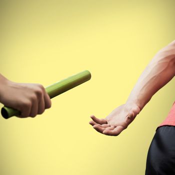 Athlete passing a baton to the partner on yellow background