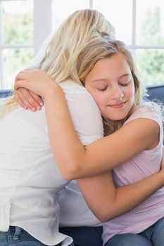 Girl with eyes closed embracing mother in house