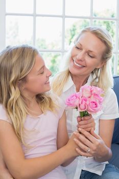 Happy mother receiving flower bouquet from loving daughter in house
