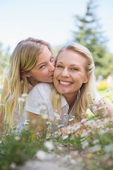 Portrait of girl kissing mother while lying in park