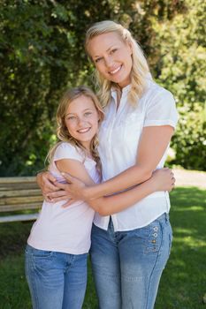 Portrait of happy mother and daughter embracing in park
