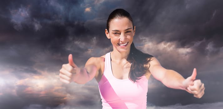 Portrait of sportswoman is smiling with thumbs up against gloomy sky