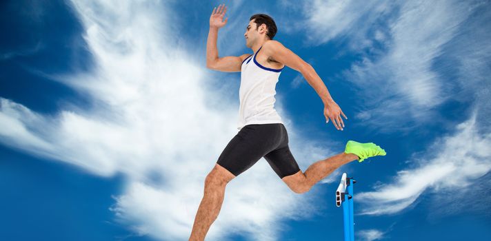 Male athlete running against blue sky with clouds