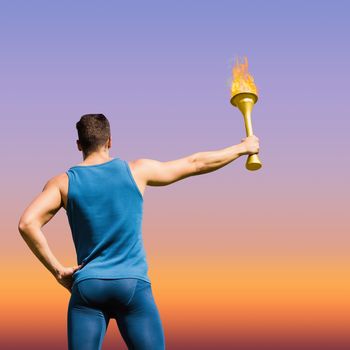 Rear view of athletic man holding the Olympic torch against sunrise sky