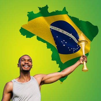 Front view of happy sportsman holding a cup  against green brazil outline with flag
