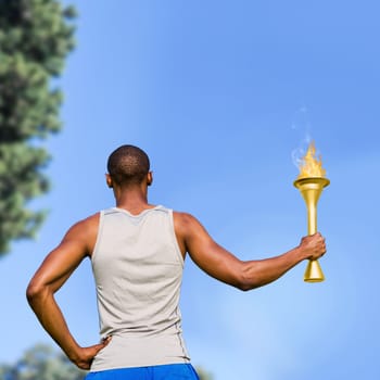 Rear view of sportsman holding a cup  against tree leaves against the sky