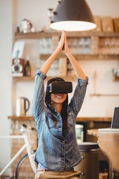 Young woman using the virtual reality headset for performing yoga at office cafeteria