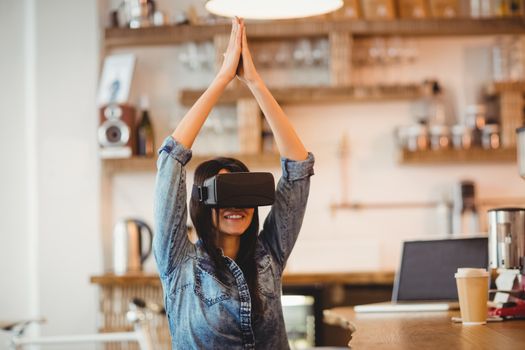 Young woman using the virtual reality headset for performing yoga at office cafeteria