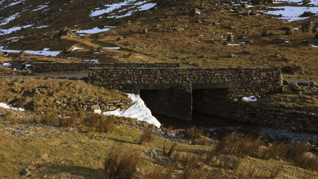 A stone bridge crossing Gatesgarthdale Beck at Moss Crag in the English Lake District national park.