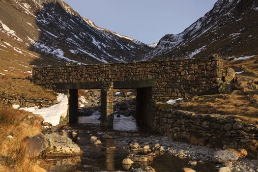 A stone bridge crossing Gatesgarthdale Beck at Moss Crag in the English Lake District national park.