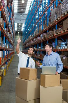 Managers are looking up and pointing shelves in a warehouse