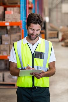 Portrait of worker is writing on clipboard in a warehouse