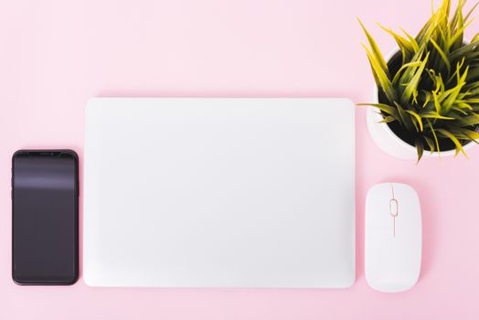 Top view of modern technology smart phone mobile and computer laptop close cover on pink background with copy space