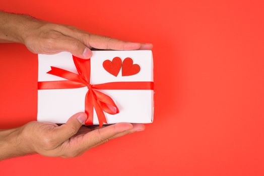 Valentine's Day Concept, Top view Flat lay, Hand holding gift box on red background with copy space for your text