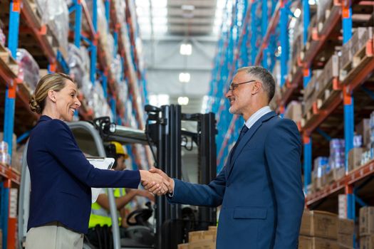 Business people are handshaking and smiling in a warehouse