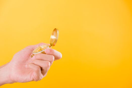 Hand holding antique brass compass isolated on yellow background with copy space for text