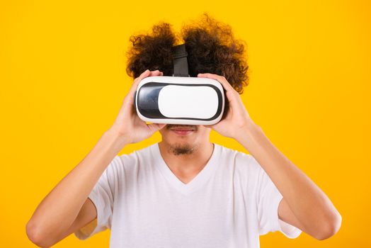 Asian handsome man with curly hair he using virtual reality headset or VR glass isolate on yellow background