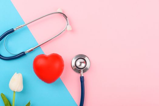 Doctor's Day concept, flat lay top view, stethoscope with red heart on pink blue background, diagnosis of heart disease with copy space for text